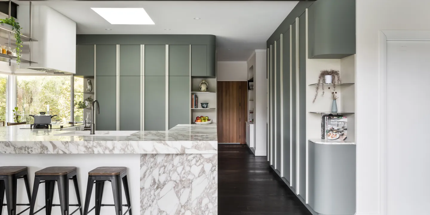Kitchen with marble bench & curved green joinery 